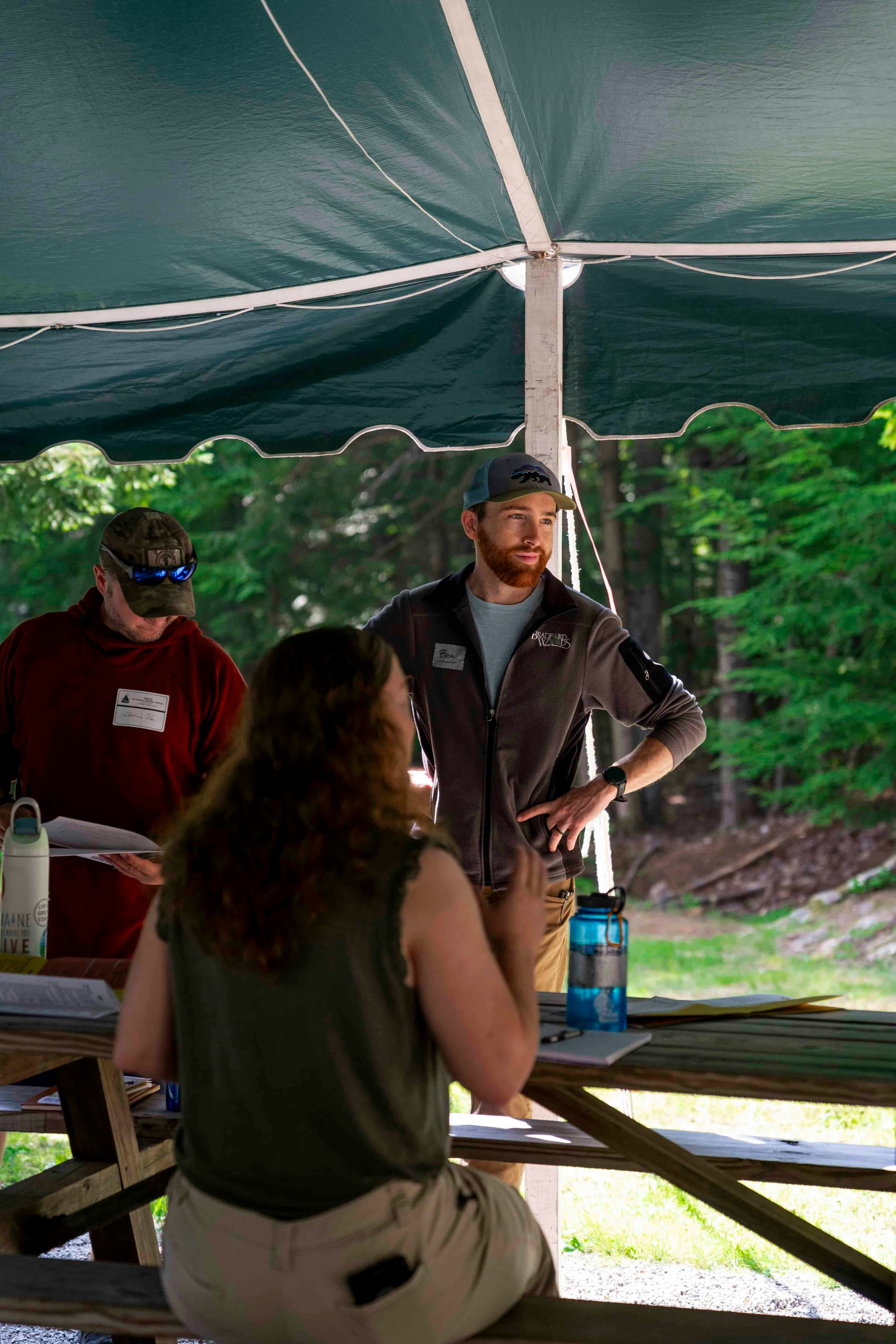 Organizers and guests talking under an outdoor event tent.